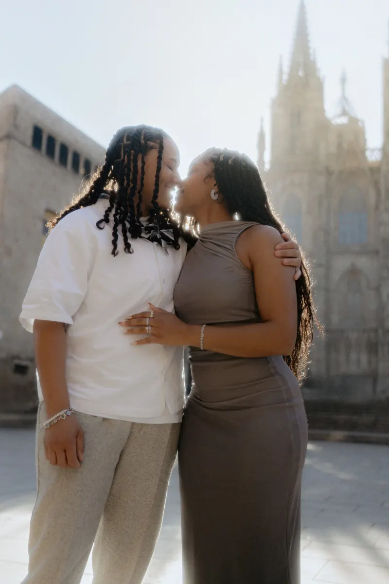 Couple shares a loving kiss outside Barcelona Cathedral, celebrating their engagement during a surprise proposal session.
