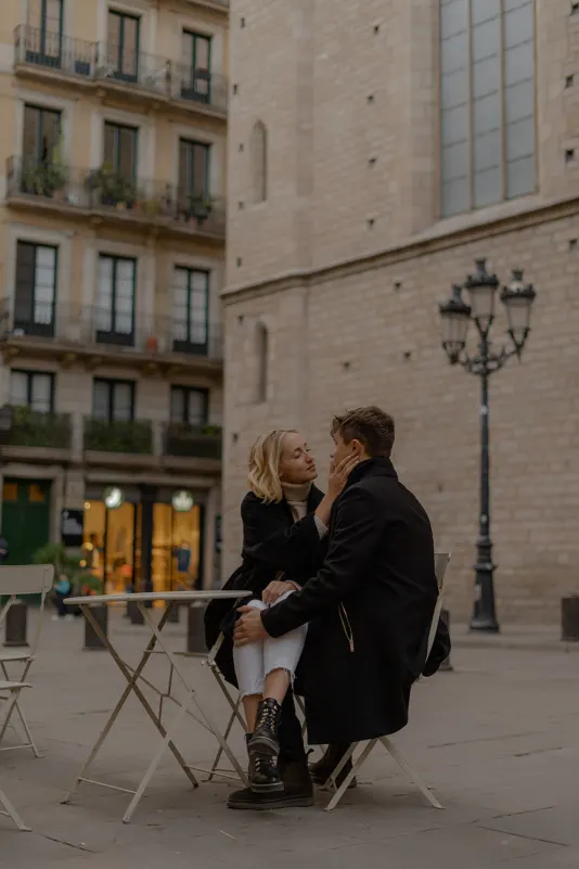 Couple shares a quiet, affectionate moment at an outdoor café table in Barcelona during a couples & engagements photoshoot.