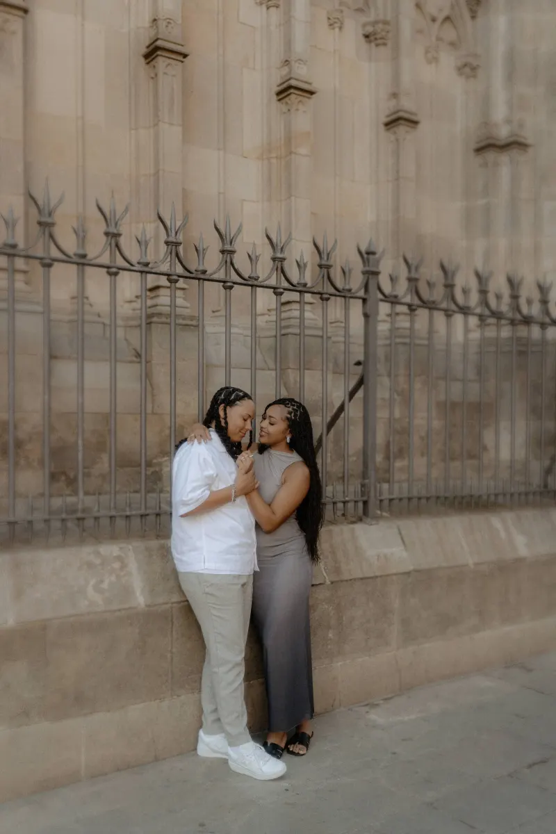Couple shares a quiet, affectionate moment by the cathedral fence during a surprise proposal photoshoot in Barcelona.