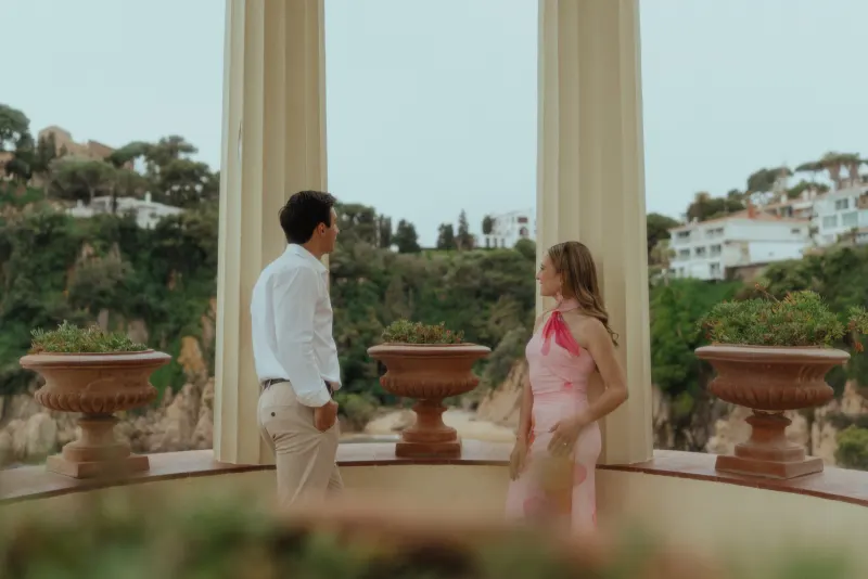 Couple shares a quiet, anticipatory moment in a seaside pavilion during a surprise proposal photoshoot.