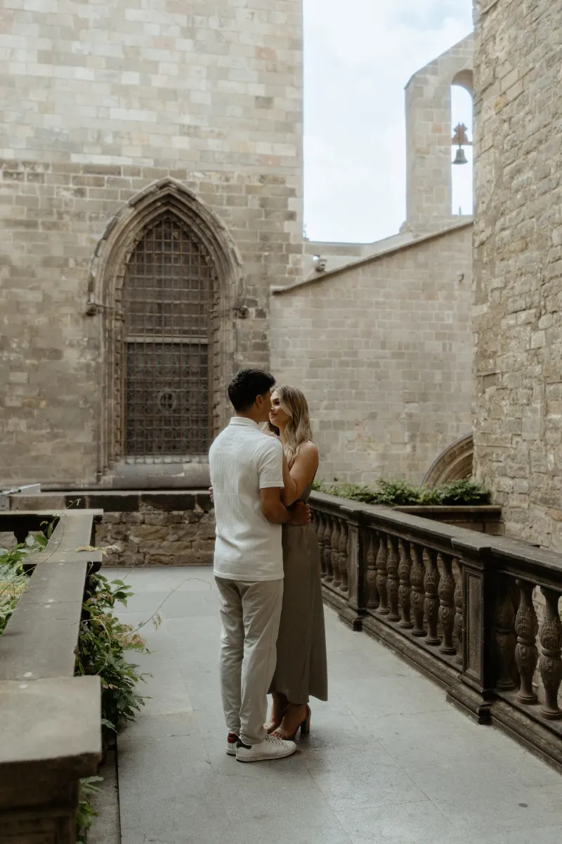 Couple shares a quiet embrace in a historic Barcelona courtyard during their Vacation Portraits photoshoot.