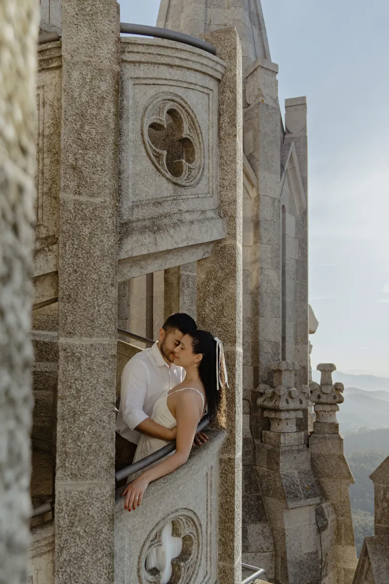 Couple shares a quiet embrace on a stone balcony of a historic castle during their couples & engagements photoshoot.