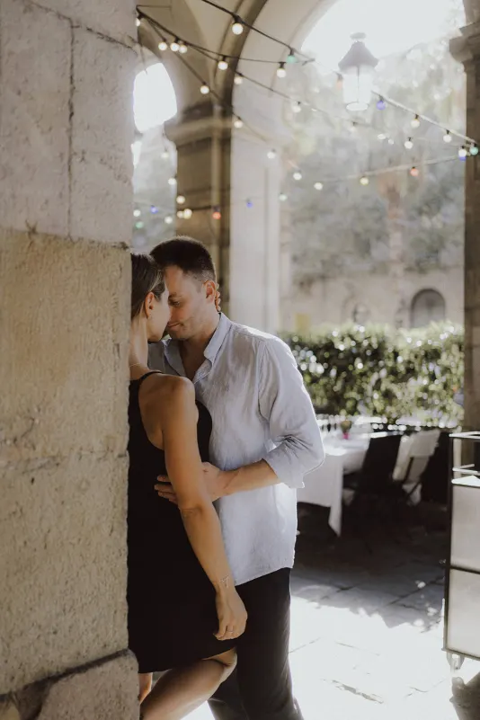 Couple shares a quiet, intimate moment beneath string lights at an outdoor café during a couples & engagements photoshoot.