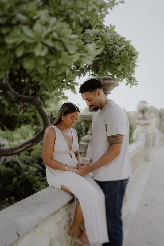 Couple shares a quiet, intimate moment during an engagement photoshoot in a lush garden setting.