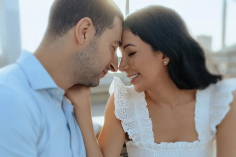 Couple shares a quiet, joyful moment forehead to forehead during a couples & engagements photoshoot by the marina.