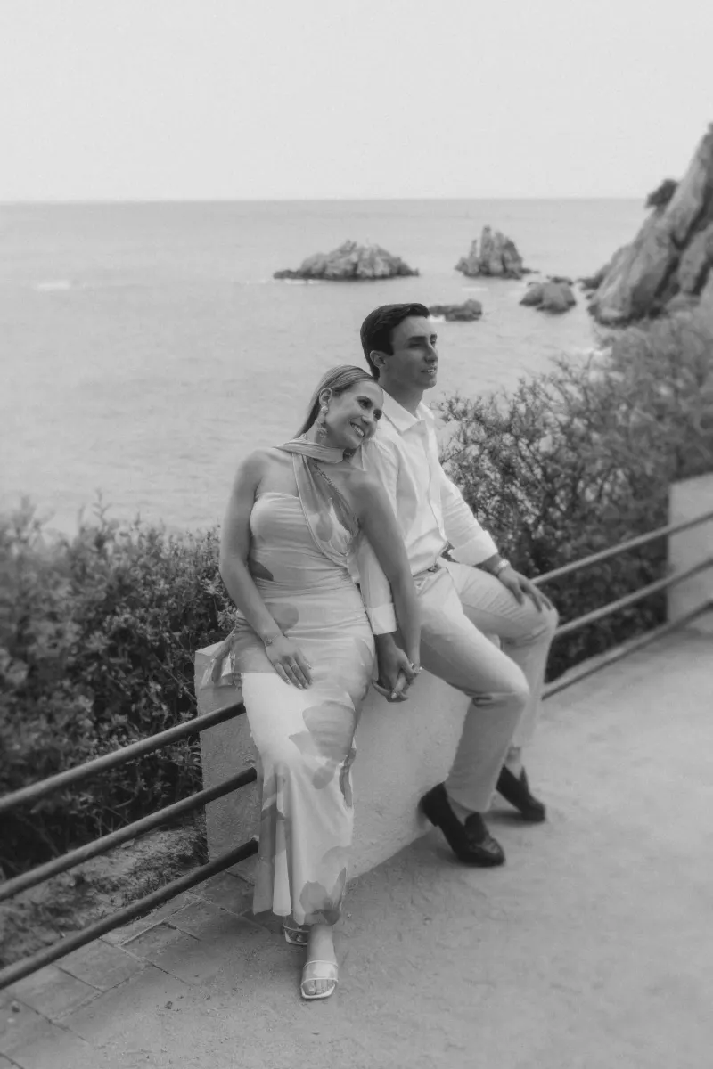 Couple shares a quiet, joyful moment holding hands by the ocean after a surprise proposal photoshoot.