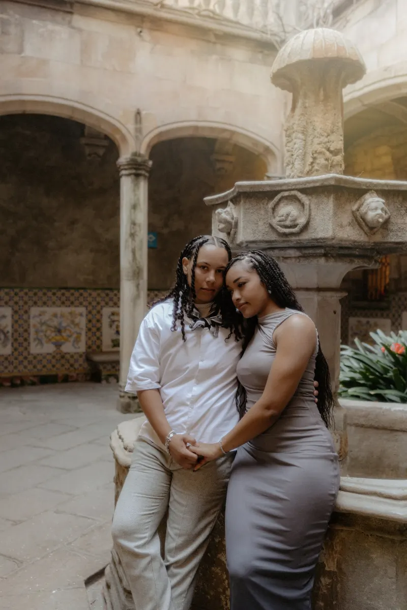 Couple shares a quiet, loving embrace by a historic stone fountain during their surprise proposal photoshoot in Barcelona.