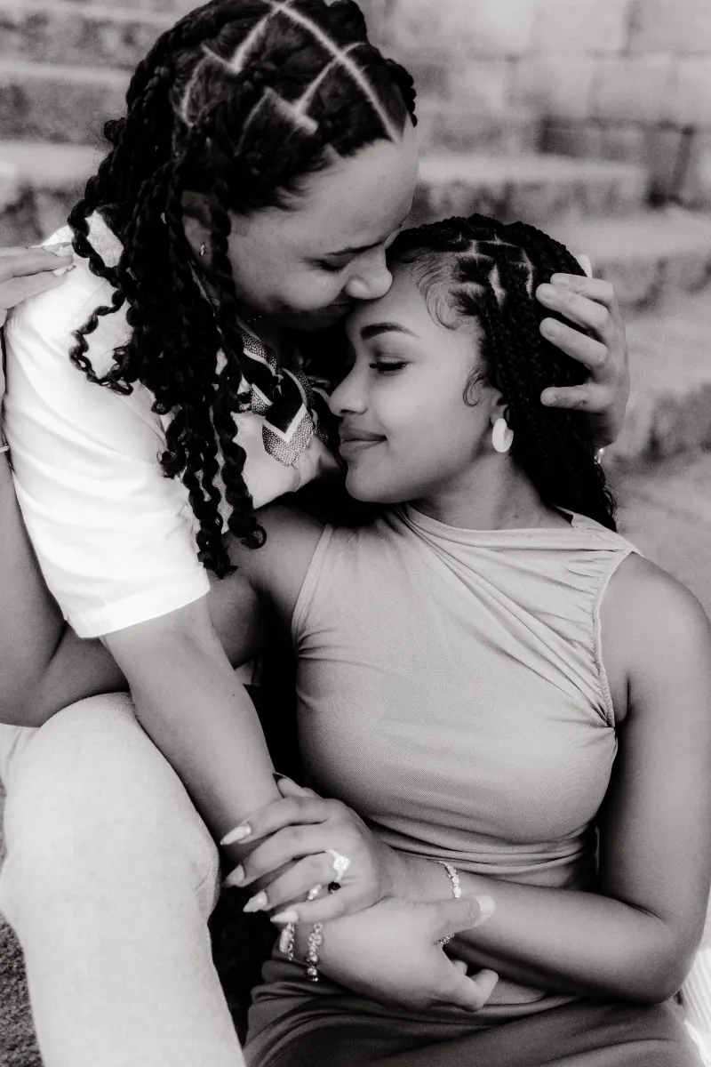 Couple shares a quiet, loving embrace on stone steps after a surprise proposal, highlighting their joy and connection.