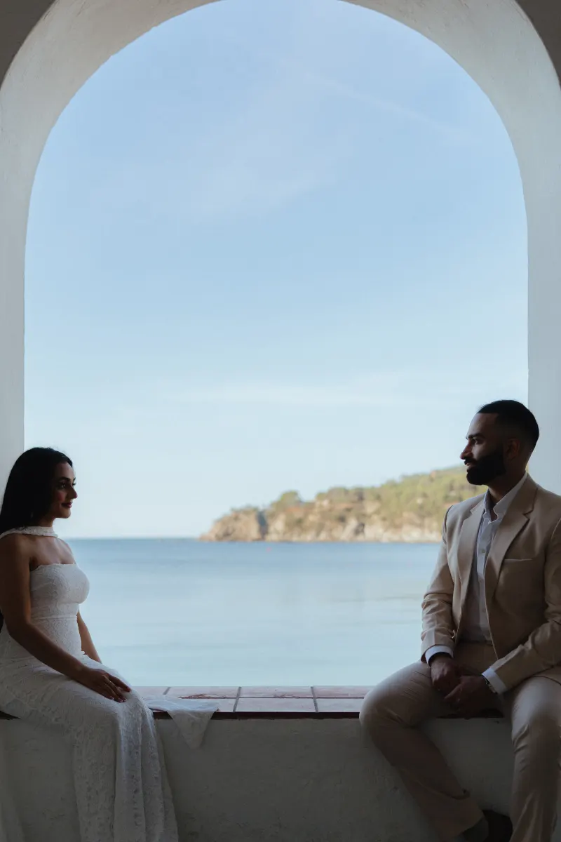 Couple shares a quiet moment by the sea during a surprise proposal photoshoot in a Mediterranean setting.