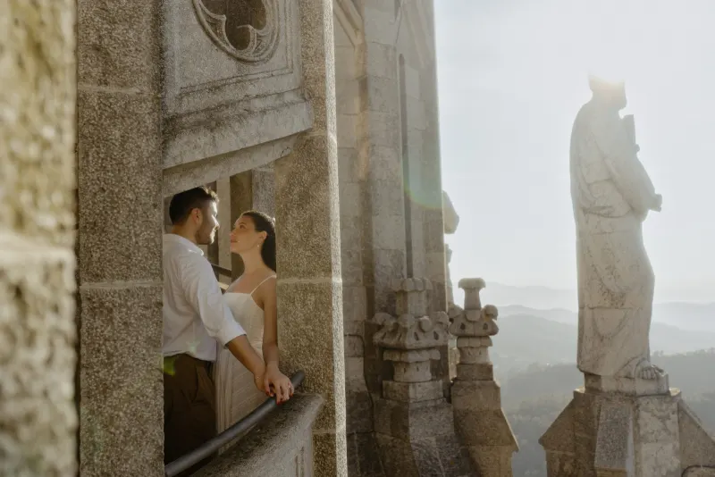 Couple shares a quiet, romantic moment on a sunlit stone balcony during their couples & engagements photoshoot.
