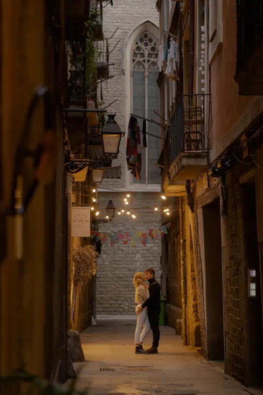 Couple shares a romantic kiss in a lantern-lit Barcelona alley during a couples & engagements photoshoot.