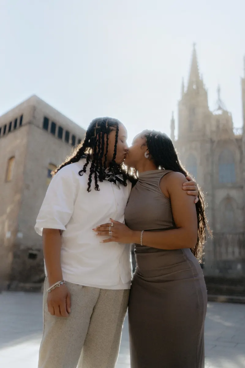 Couple shares a romantic kiss outside Barcelona Cathedral during a surprise proposal photoshoot session.