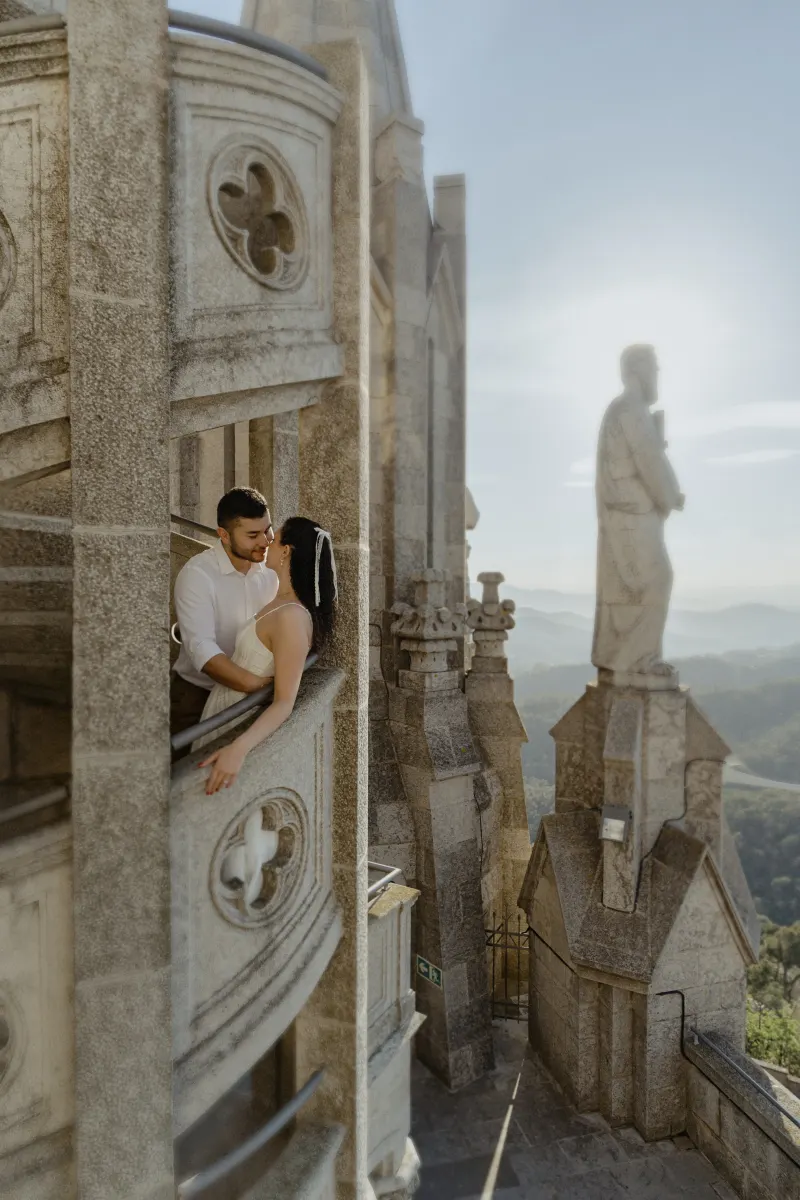 Couple shares a romantic moment on a stone balcony, framed by historic architecture during their engagement photoshoot.