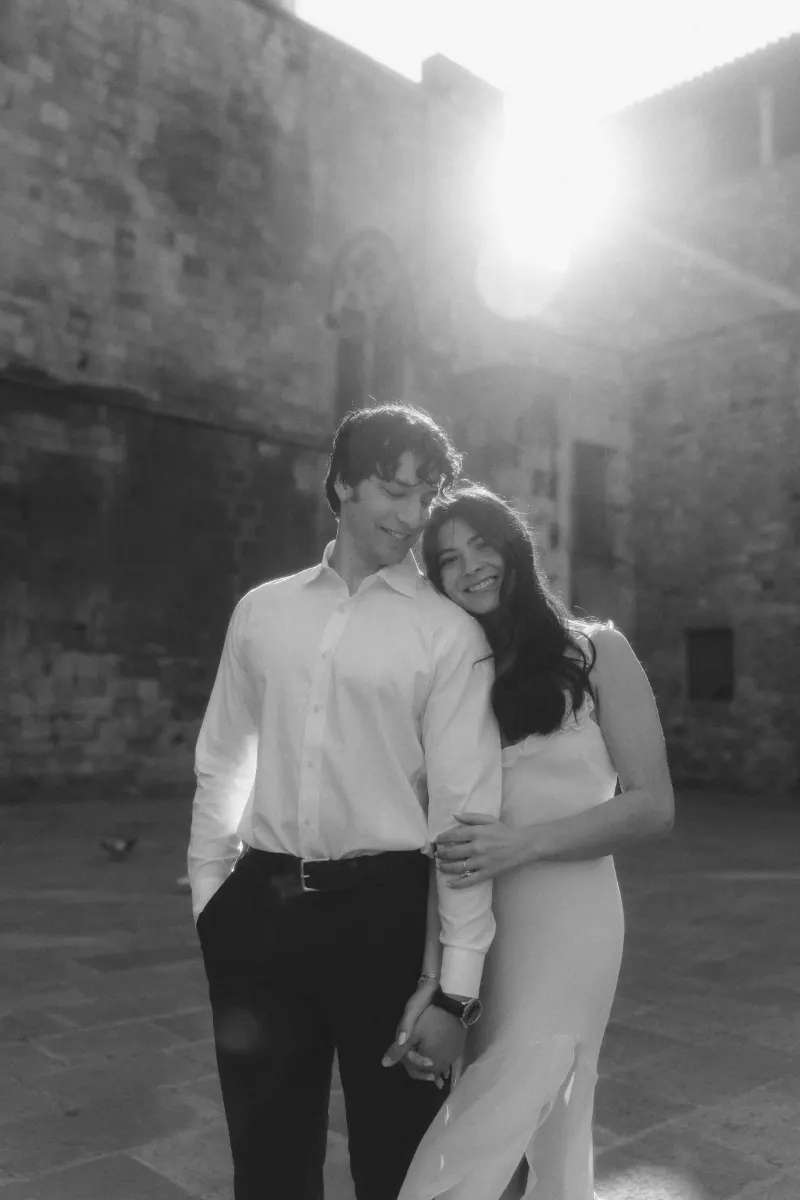 Couple shares a soft embrace and smiles in golden sunlight during a romantic couples & engagements photoshoot in the city.