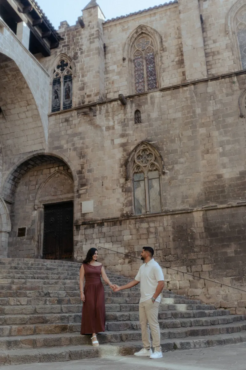 Couple shares a sweet moment holding hands on stone steps during a couples & engagements photoshoot in a historic courtyard.