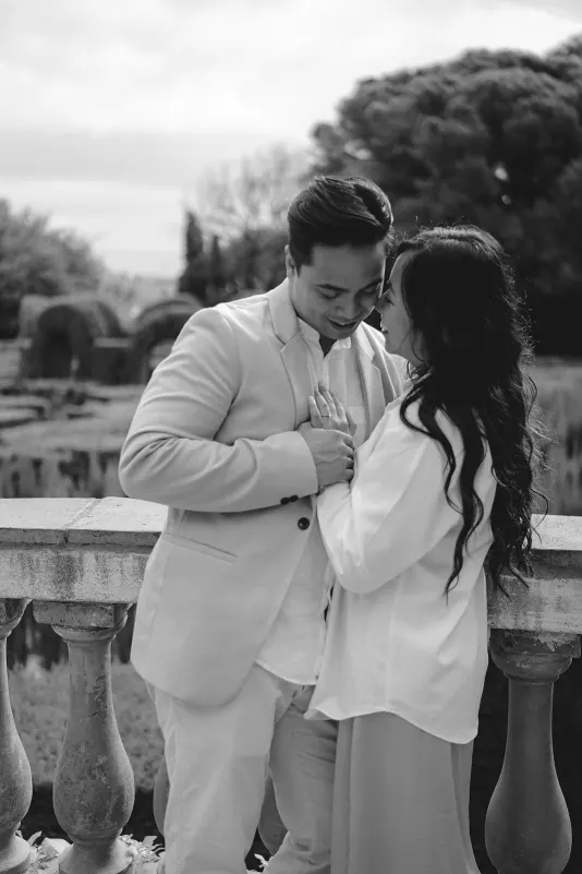 Couple shares a tender, intimate moment by a stone railing during a couples & engagements photoshoot in the park.