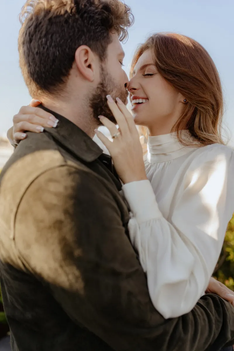 Couple shares a tender, joyful moment in close embrace during a couples & engagements photoshoot outdoors.