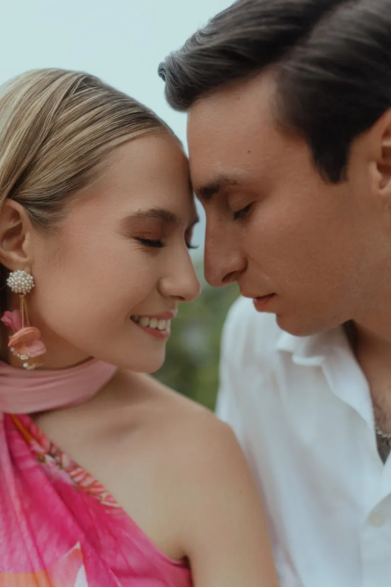 Couple shares a tender, joyful moment with foreheads touching during a surprise proposal photoshoot by the sea.