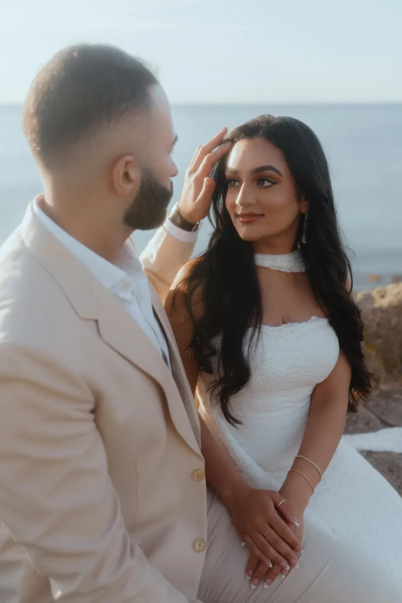 Couple shares a tender moment by the water after a surprise proposal photoshoot, radiating joy and love.