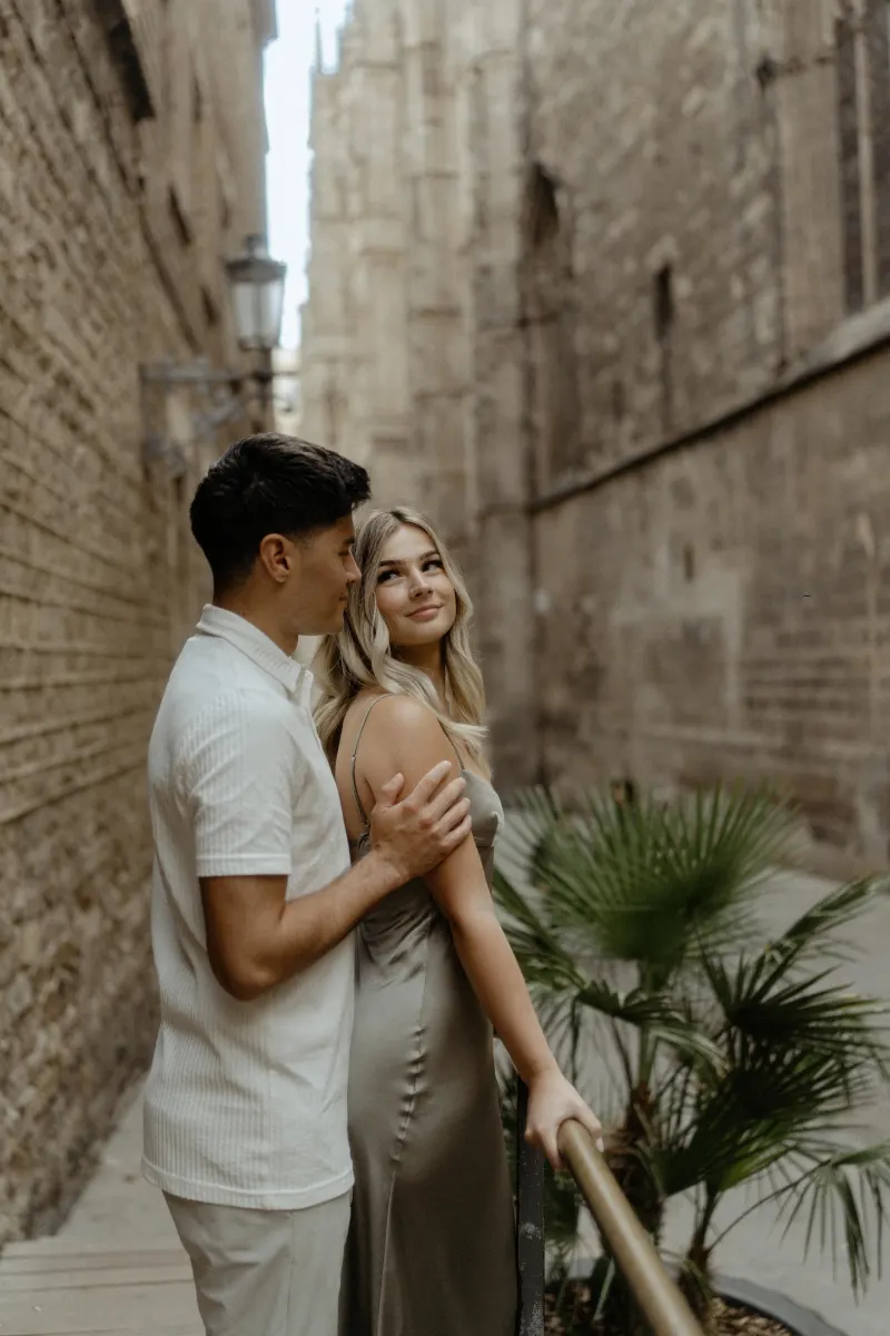 Couple shares a tender moment in a quiet Barcelona alley during their Vacation Portraits photoshoot.