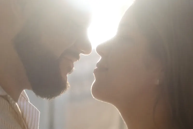 Couple shares a tender, sunlit moment up close during their engagement photoshoot, radiating warmth and connection.