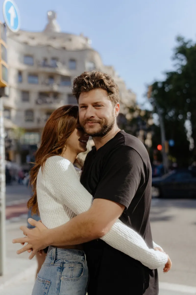 Couple shares a warm embrace on a sunny city street, captured during a couples & engagements photoshoot.