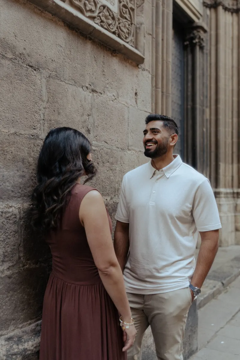 Couple shares a warm smile together during their engagement photoshoot in a historic European alleyway.