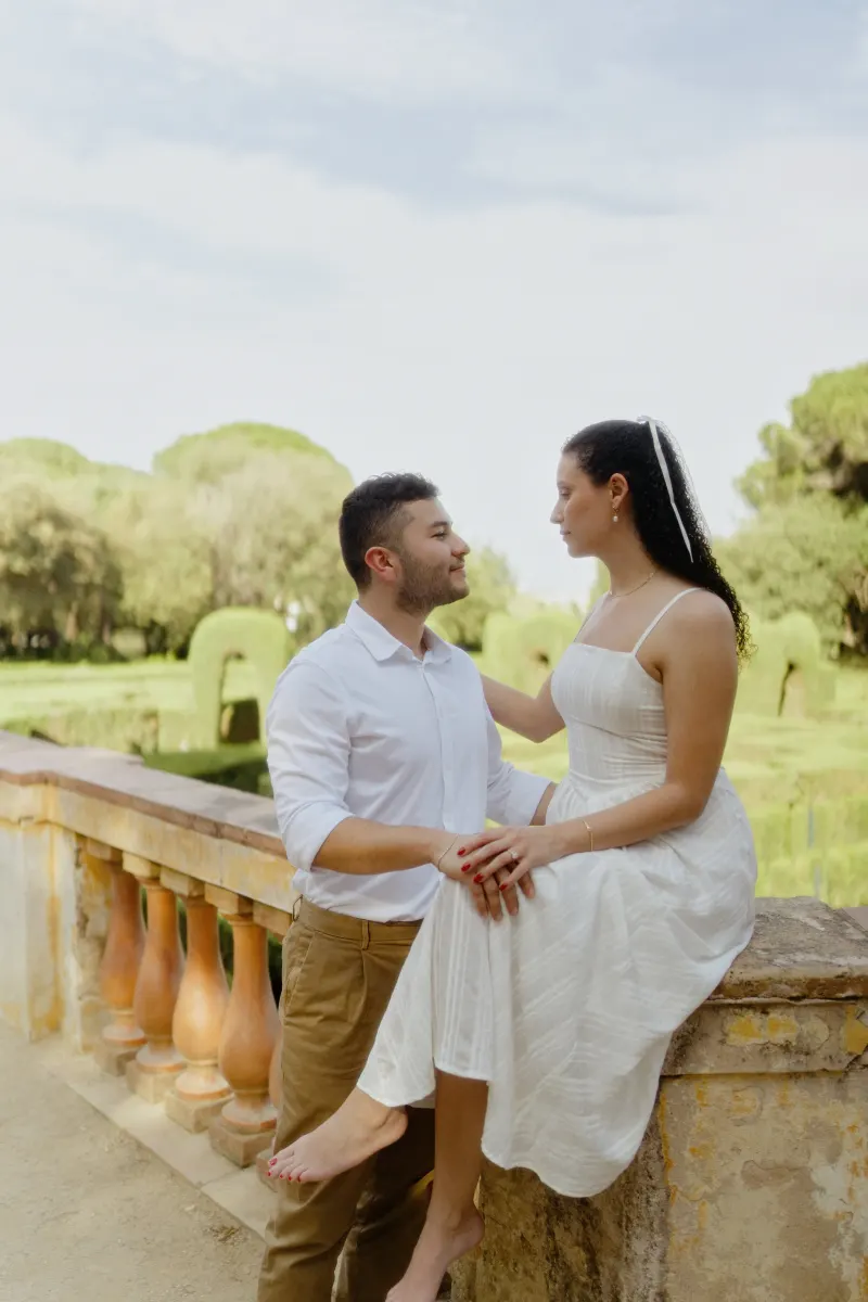 Couple shares an affectionate gaze on a sunlit garden terrace during a couples & engagements photoshoot.