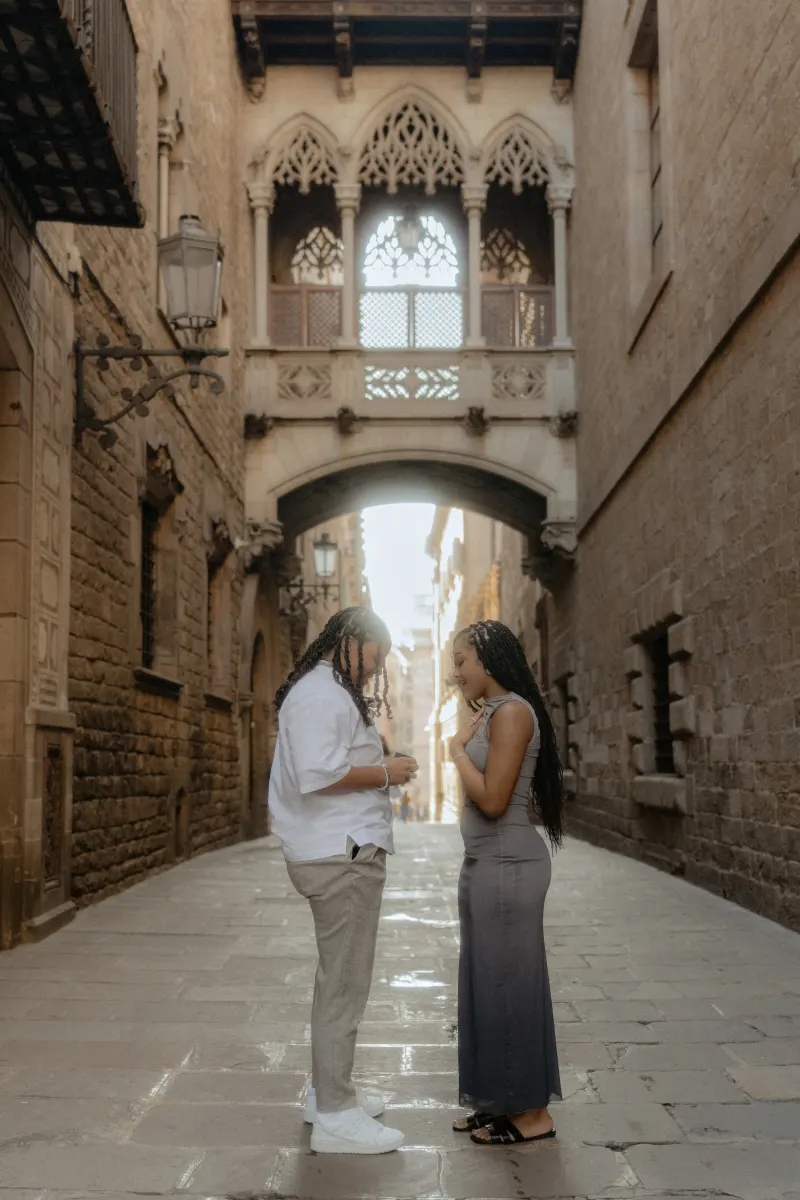 Couple shares an emotional proposal moment beneath Barcelona’s iconic Gothic bridge during a surprise proposal photoshoot.