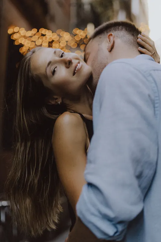 Couple shares an intimate embrace under city lights, capturing romance during a couples & engagements photoshoot.