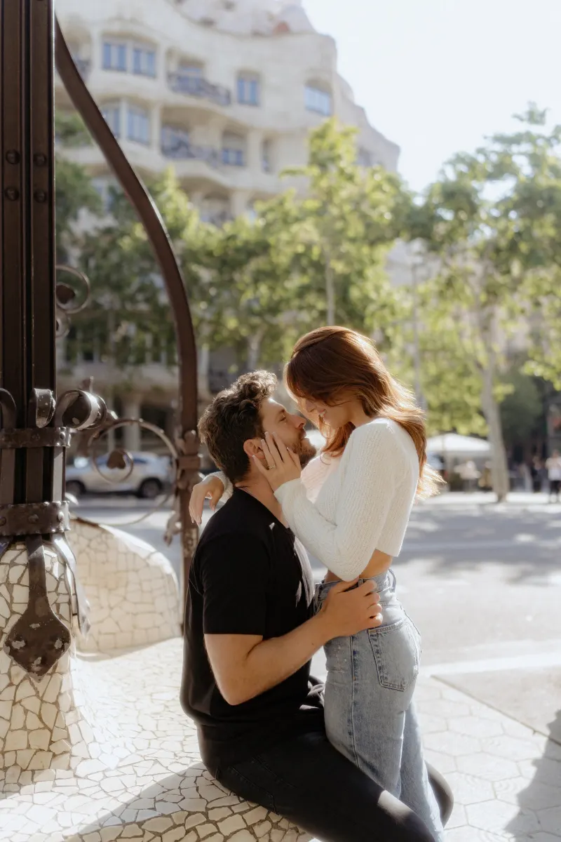 Couple shares an intimate, joyful moment on a sunlit city bench during a couples & engagements photoshoot.