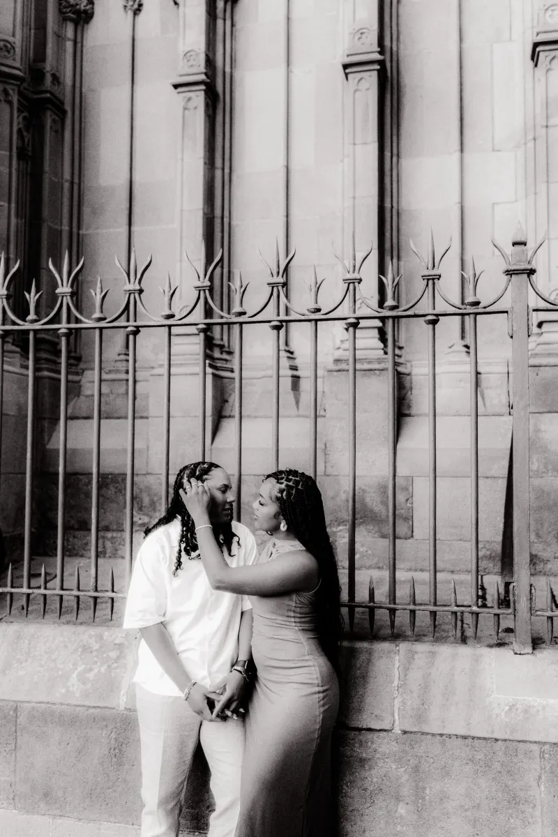 Couple shares an intimate moment by the cathedral gates during a surprise proposal photoshoot in Barcelona.