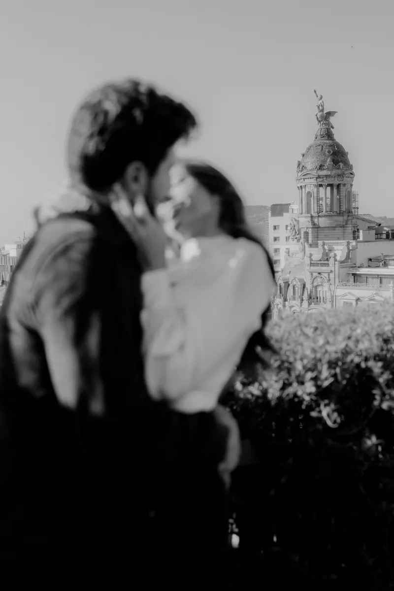 Couple shares an intimate rooftop moment with city architecture in the background during a couples & engagements session.