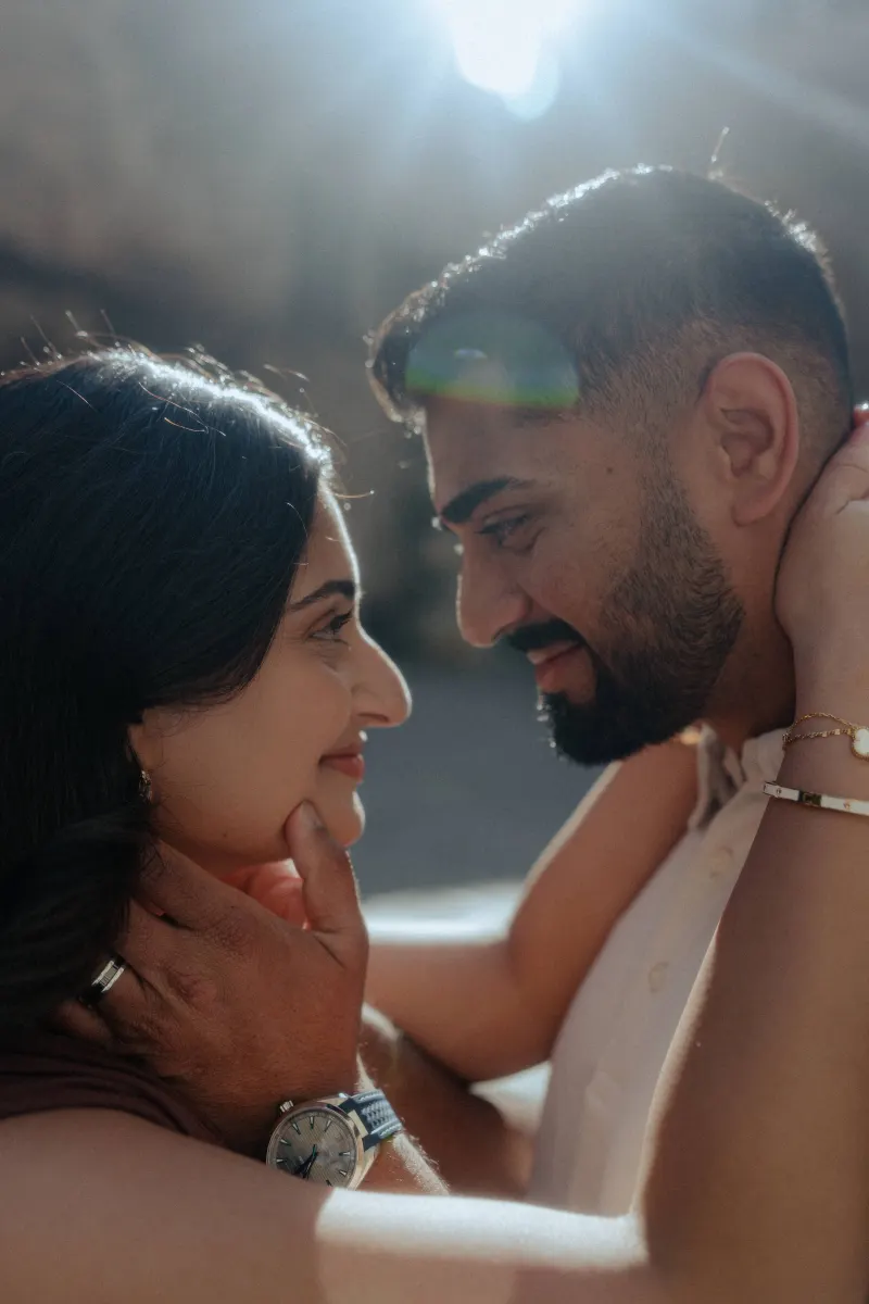 Couple shares an intimate, sunlit moment, gazing into each other's eyes during a couples & engagements photoshoot.