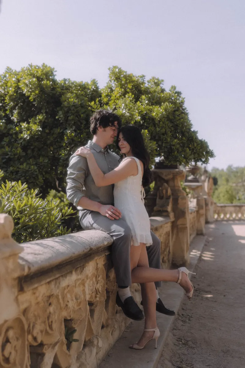 Couple sharing a gentle embrace on a sunlit stone terrace during a couples & engagements photoshoot.