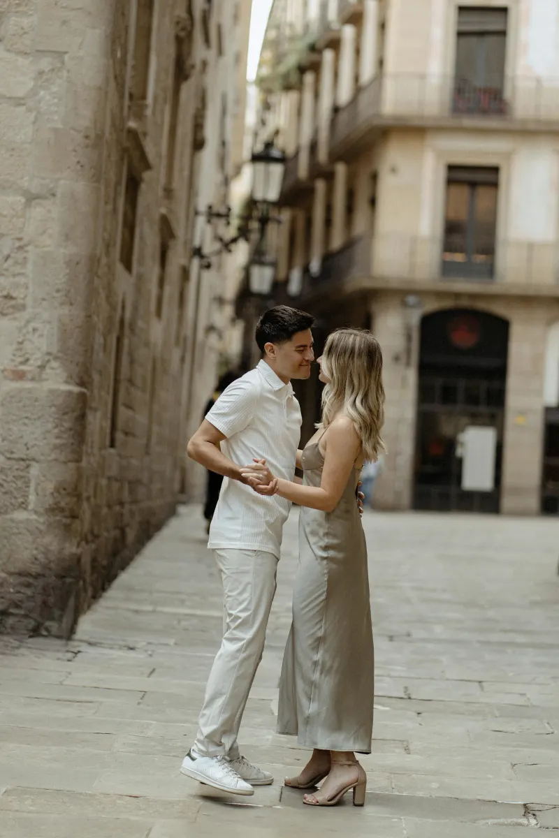Couple sharing a joyful dance in a quiet Barcelona alley during a Vacation Portraits photoshoot.