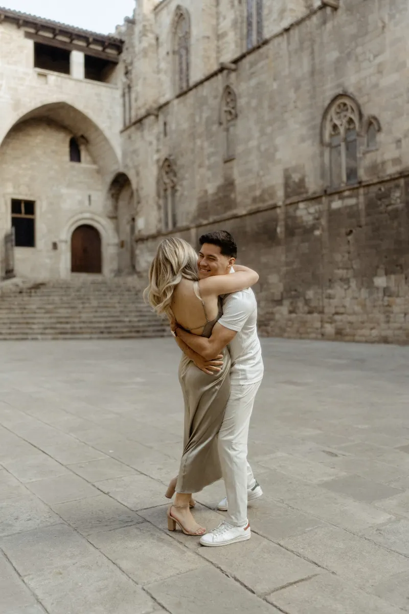 Couple sharing a joyful embrace in a historic Barcelona courtyard during their Vacation Portraits photoshoot.