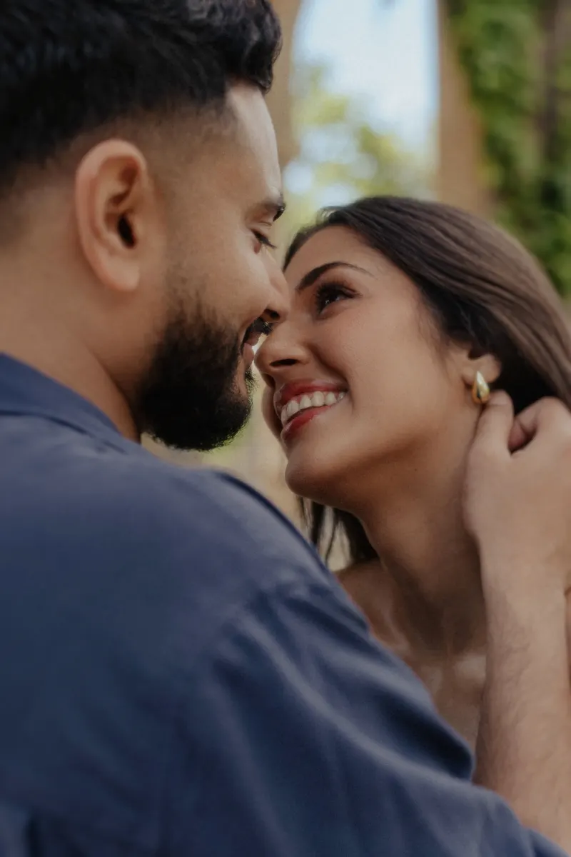 Couple sharing a joyful, intimate moment as they smile at each other during a couples & engagements photoshoot outdoors.