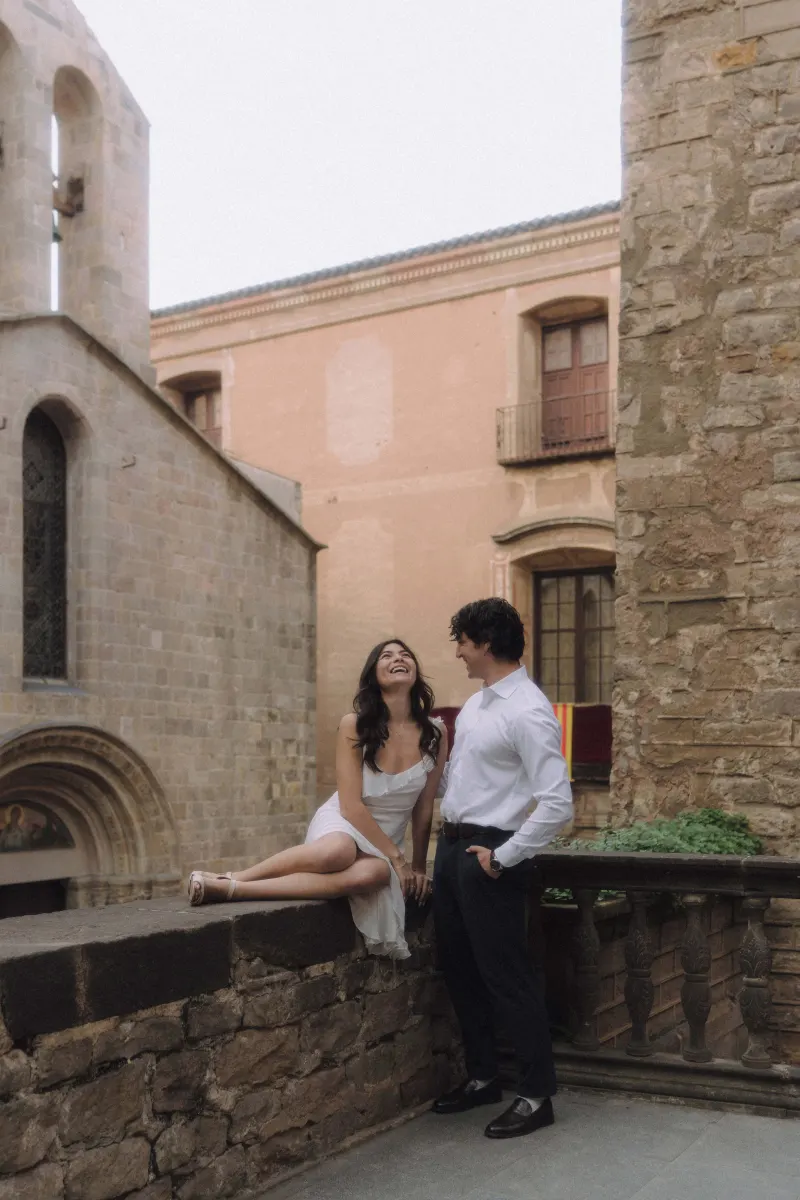 Couple sharing a joyful laugh in a historic courtyard during a couples & engagements photoshoot in the city.