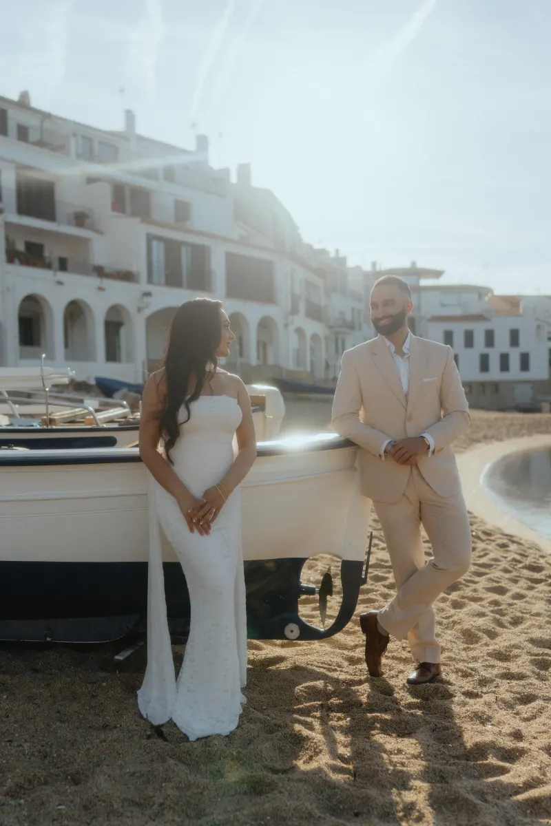Couple sharing a joyful moment by a boat on the beach during a surprise proposal photoshoot in a Mediterranean village.