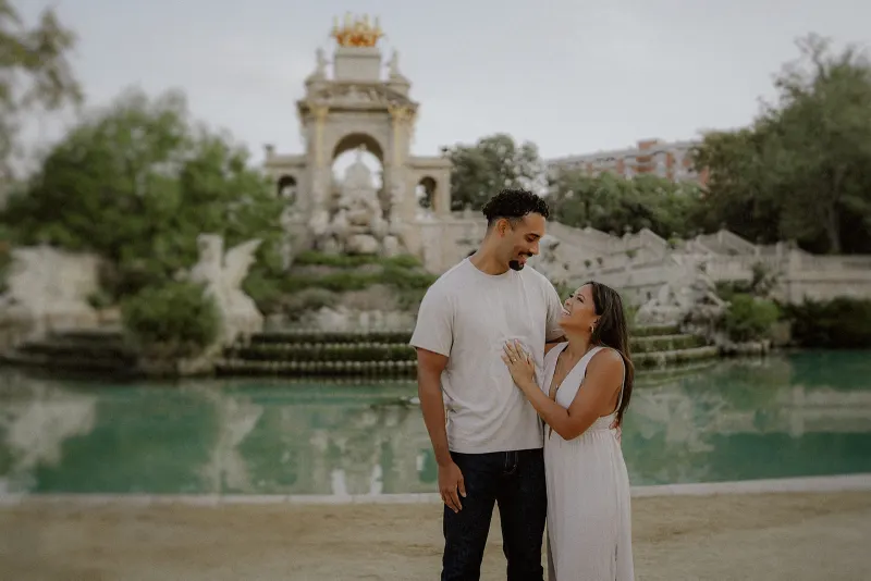 Couple sharing a joyful moment by the fountain at Parc de la Ciutadella during a couples & engagements photoshoot.