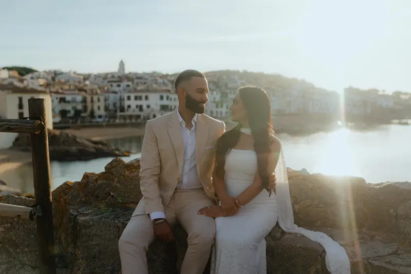 Couple sharing a joyful moment by the seaside at sunset during a surprise proposal photoshoot in a picturesque village.