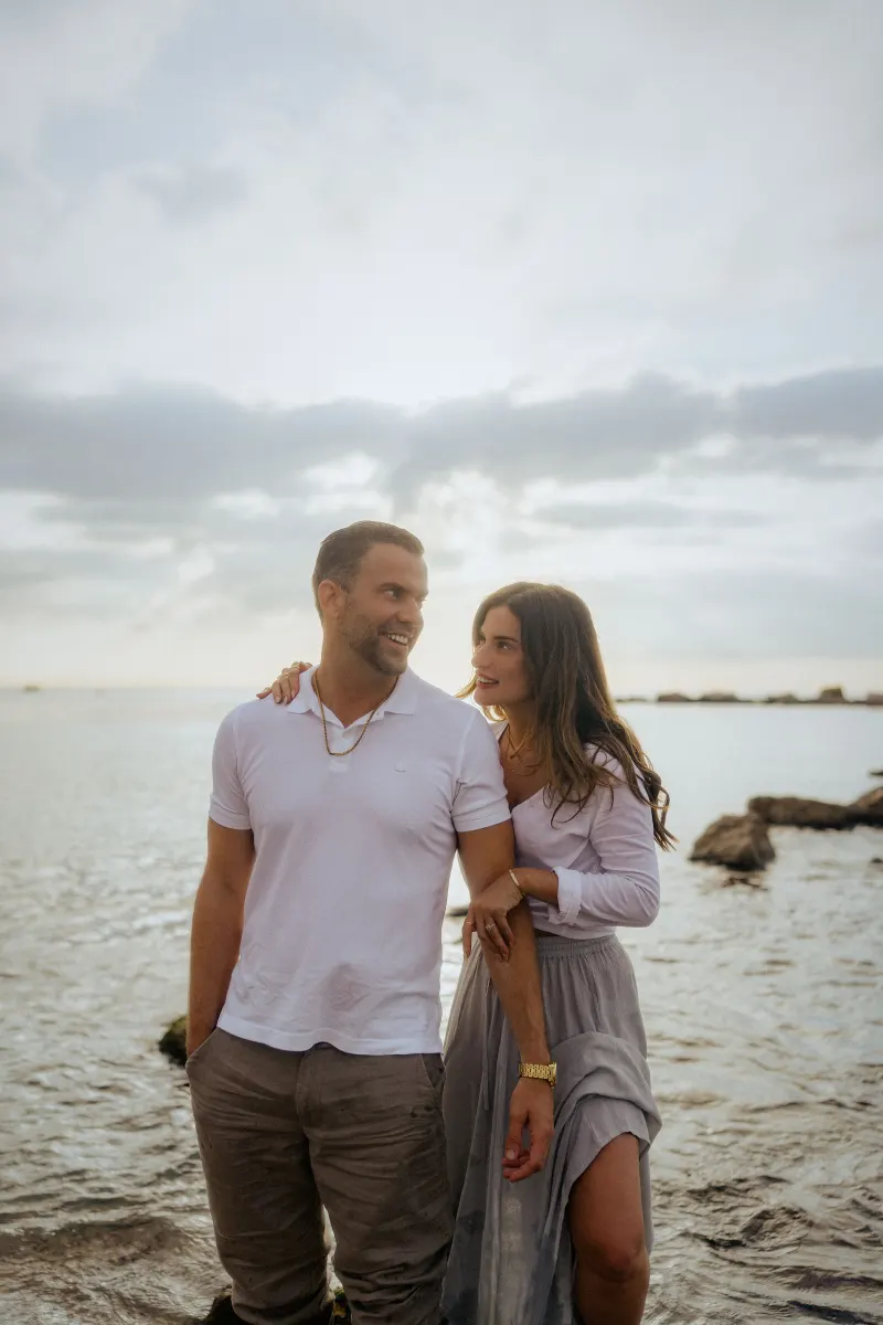 Couple sharing a joyful moment by the water’s edge, captured during a couples & engagements photoshoot.