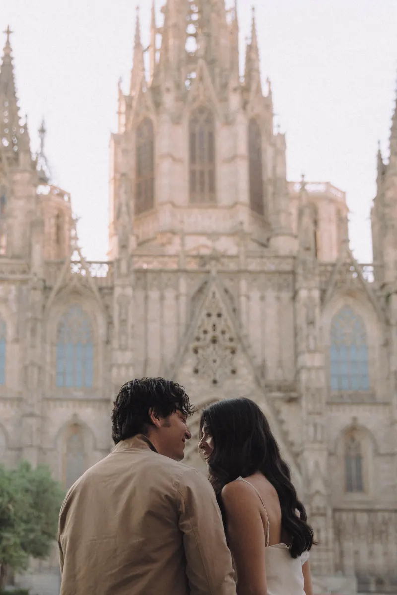 Couple sharing a joyful moment in front of a historic cathedral during an engagement photoshoot.