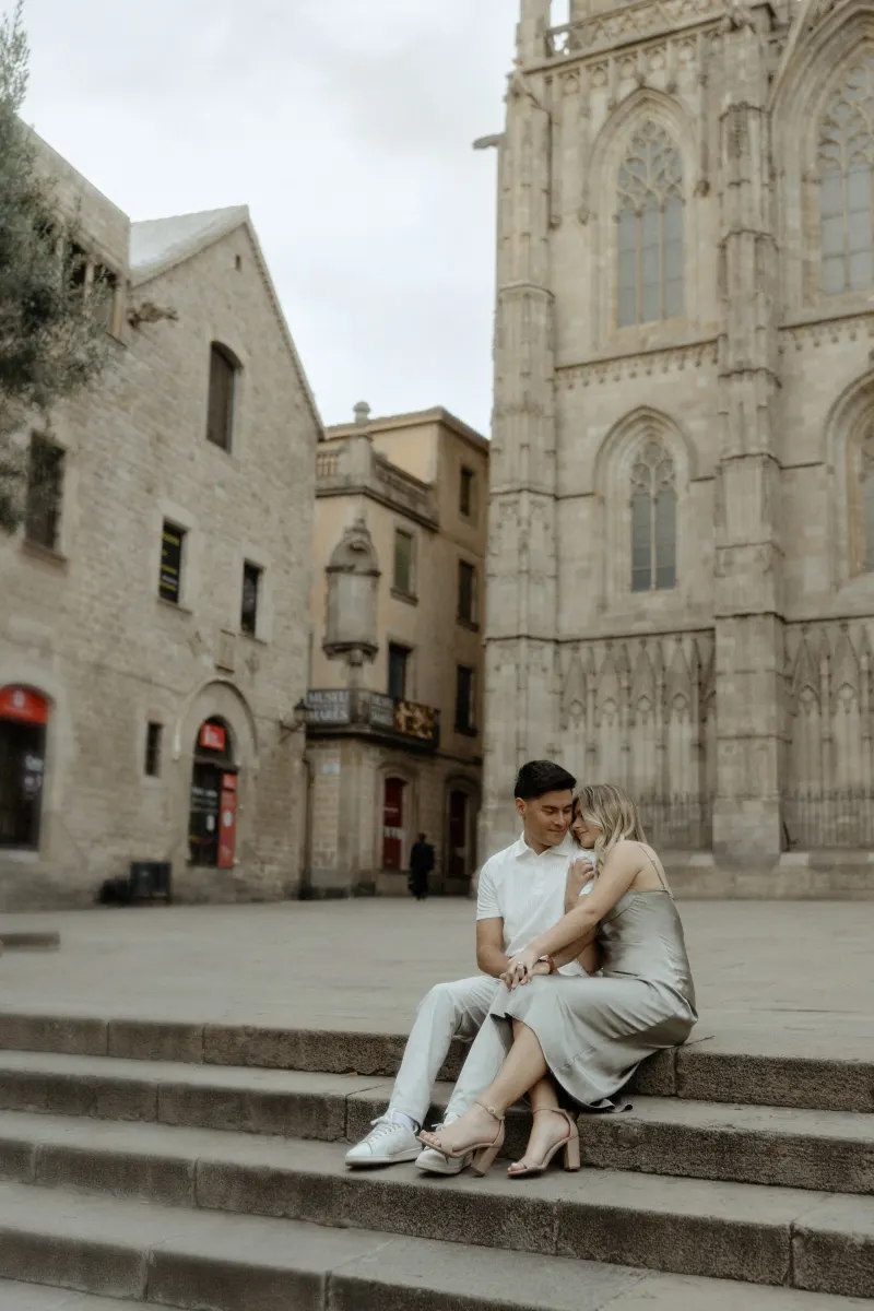 Couple sharing a loving embrace on stone steps in front of Barcelona’s cathedral during a Vacation Portraits session.