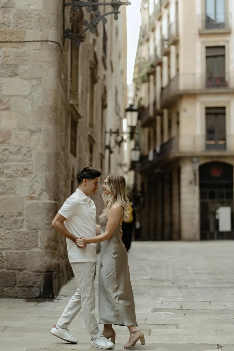 Couple sharing a loving gaze and holding hands in a quiet Barcelona street during a Vacation Portraits photoshoot.