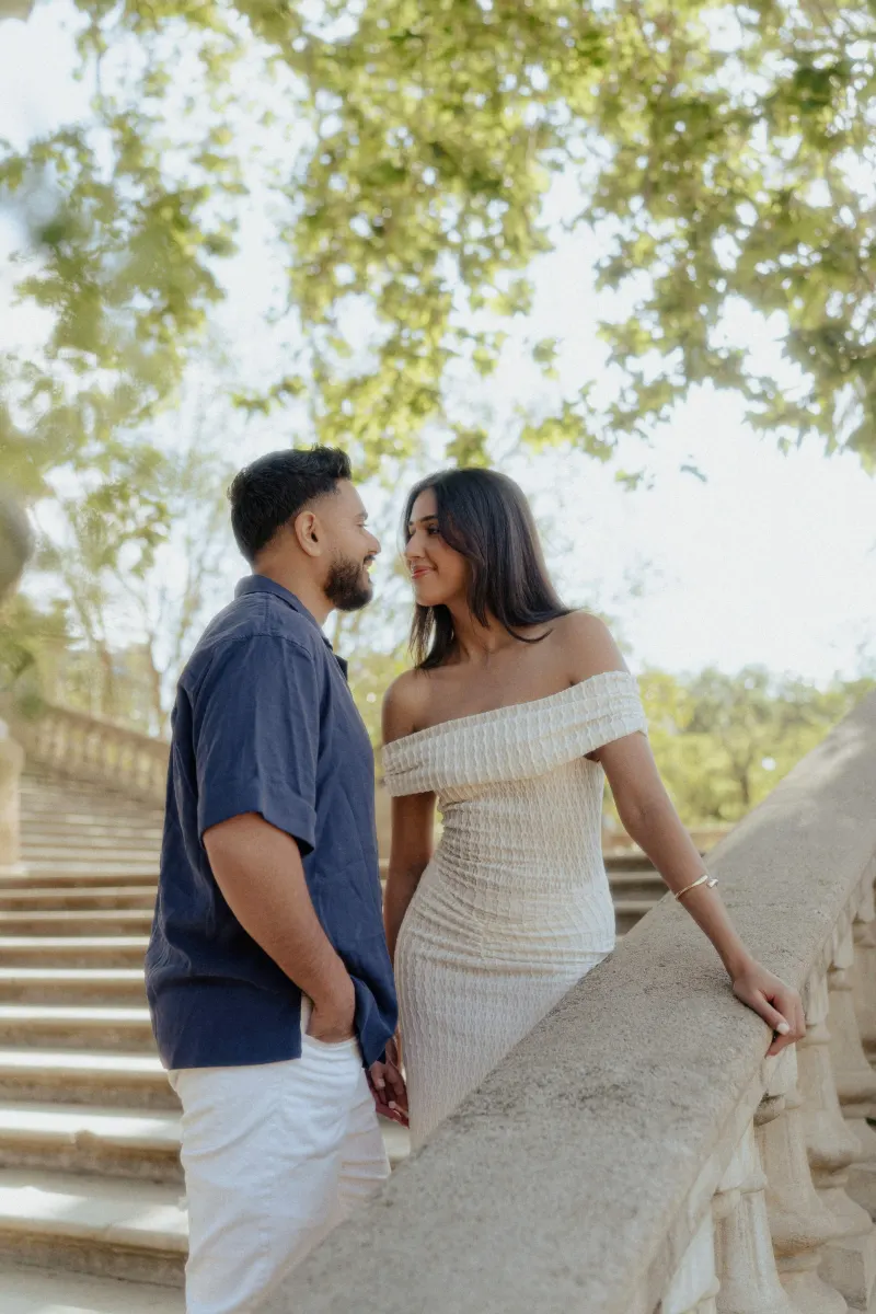 Couple sharing a loving gaze on sunlit stone steps, captured during a romantic couples & engagements photoshoot outdoors.