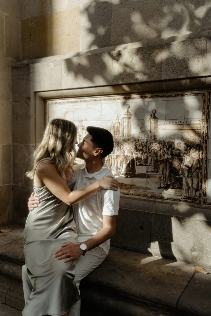 Couple sharing a loving gaze while sitting together on a sunlit bench in Barcelona during a Vacation Portraits session.
