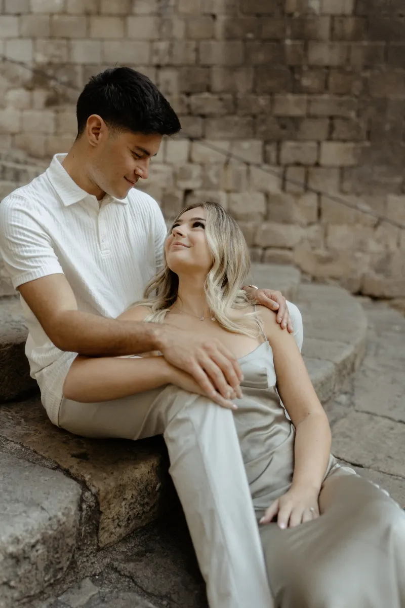 Couple sharing a loving gaze while sitting together on stone steps in Barcelona during a Vacation Portraits photoshoot.
