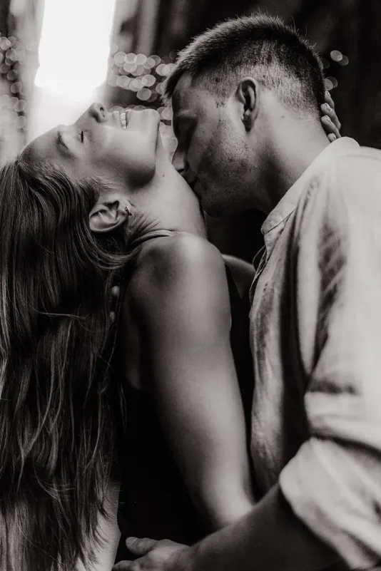 Couple sharing a passionate, joyful moment as he kisses her neck during a couples & engagements photoshoot downtown.